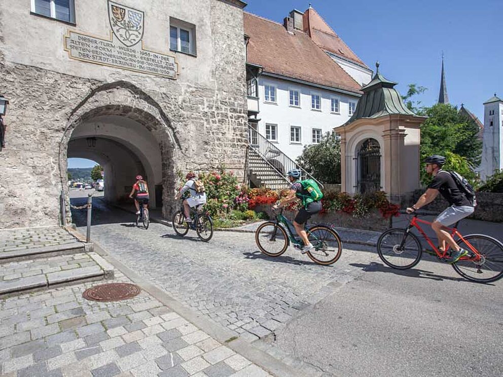 4 Radfahrer fahren durch ein mittelalterlisches Stadttor
