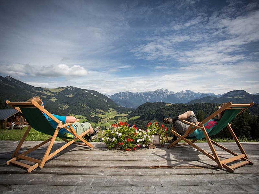 2 Menschen im Liegestuhl vor der Bergkulisse