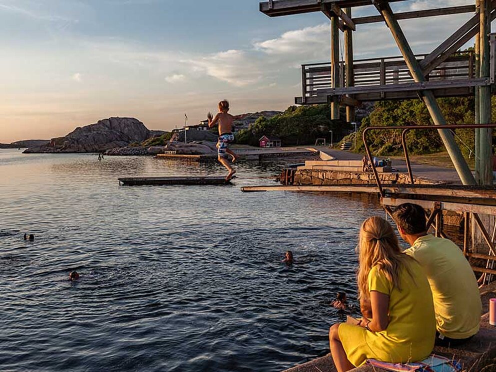 Ein Bub springt von einem Sprungbrett ins Wasser eines Naturfreibades in Schweden.