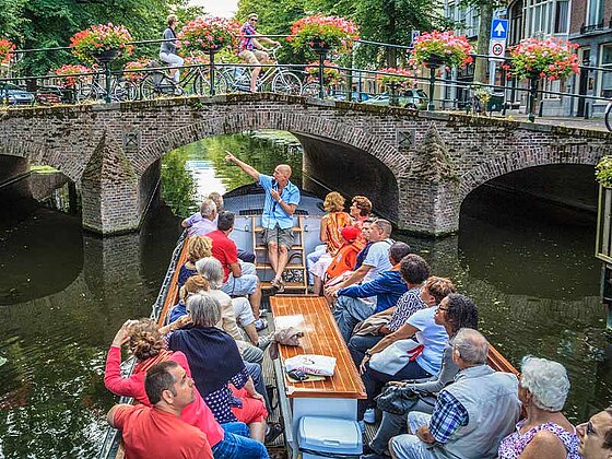 ein Gruppe am Schiff mit Guide, im Hintergrund eine Brücke mit Radfahrern darauf