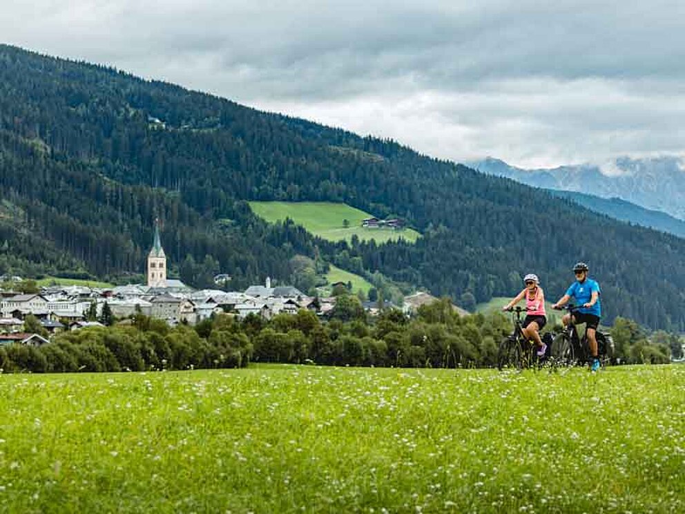 2 Radfahrer in ländlicher Umgebung, im Hintergrund der Ort Radstadt