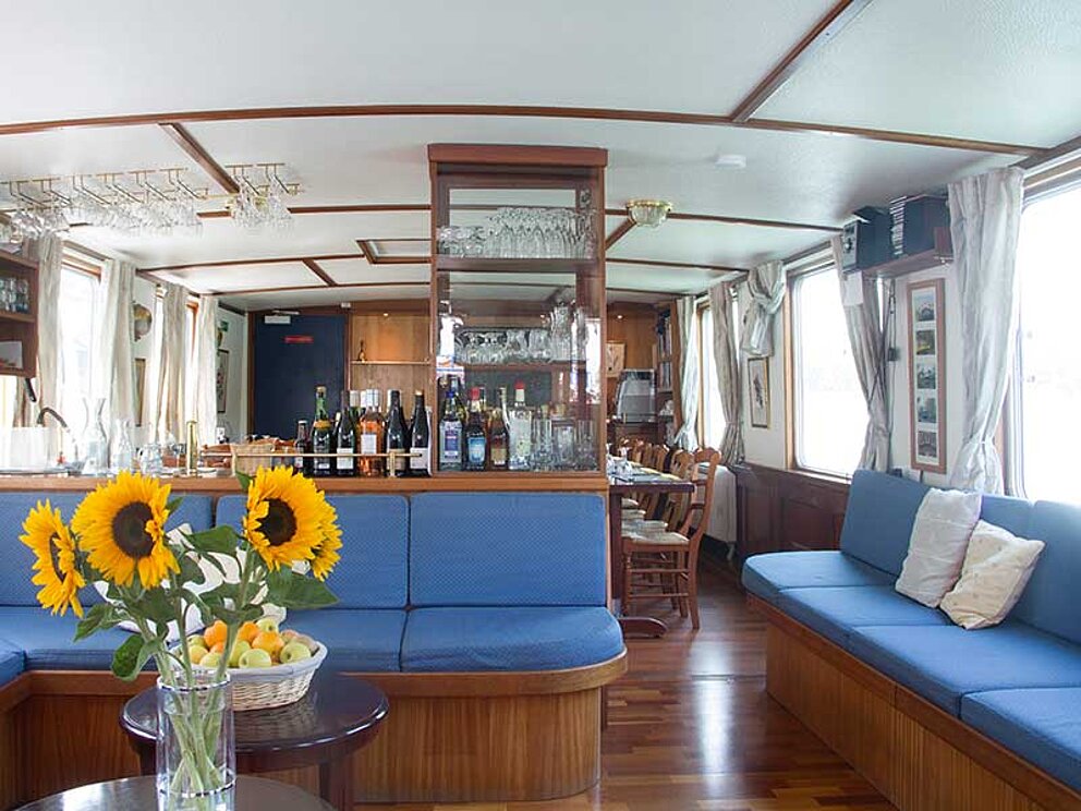 Salon mit blauen Sitzmöglichkeiten auf dem Schiff Caprice in Frankreich