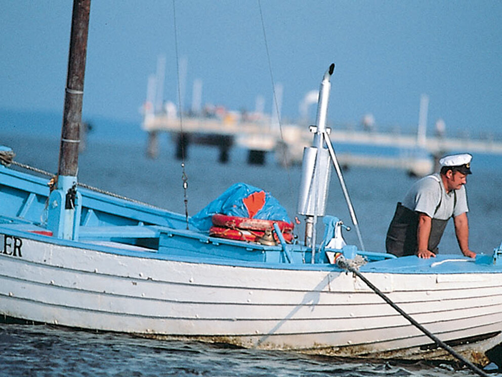 Fischer mit Kappe in einem Fischkutter in einem Ostseehafen