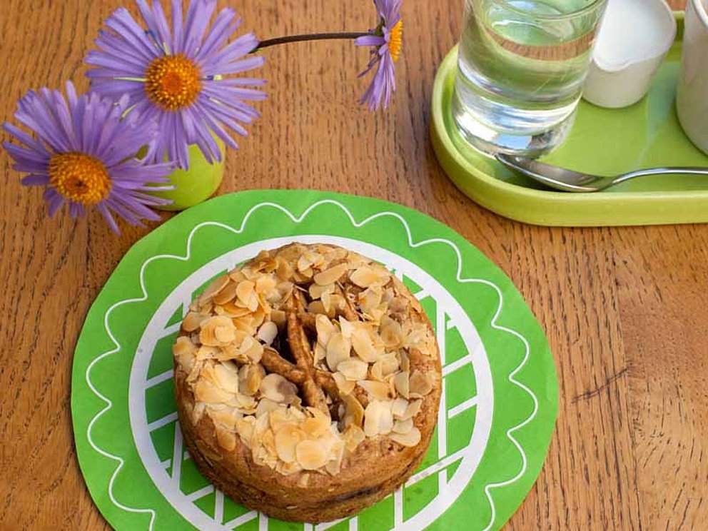 eine kleine Linzer Torte und eine Tasse Kaffee mit Blumendeko am Kaffeehaustisch