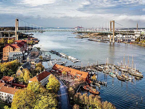 Blick auf Göteborg. Eine große Brücke überspannt die Einfahrt zum Hafen. Im Vordergrund Segelboote und Frachtschiffe