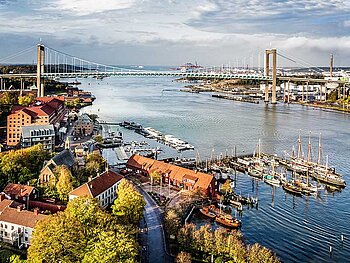 Blick auf Göteborg. Eine große Brücke überspannt die Einfahrt zum Hafen. Im Vordergrund Segelboote und Frachtschiffe