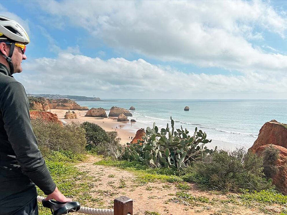 ein Radfahrer blickt über die Küste mit Sandstrand