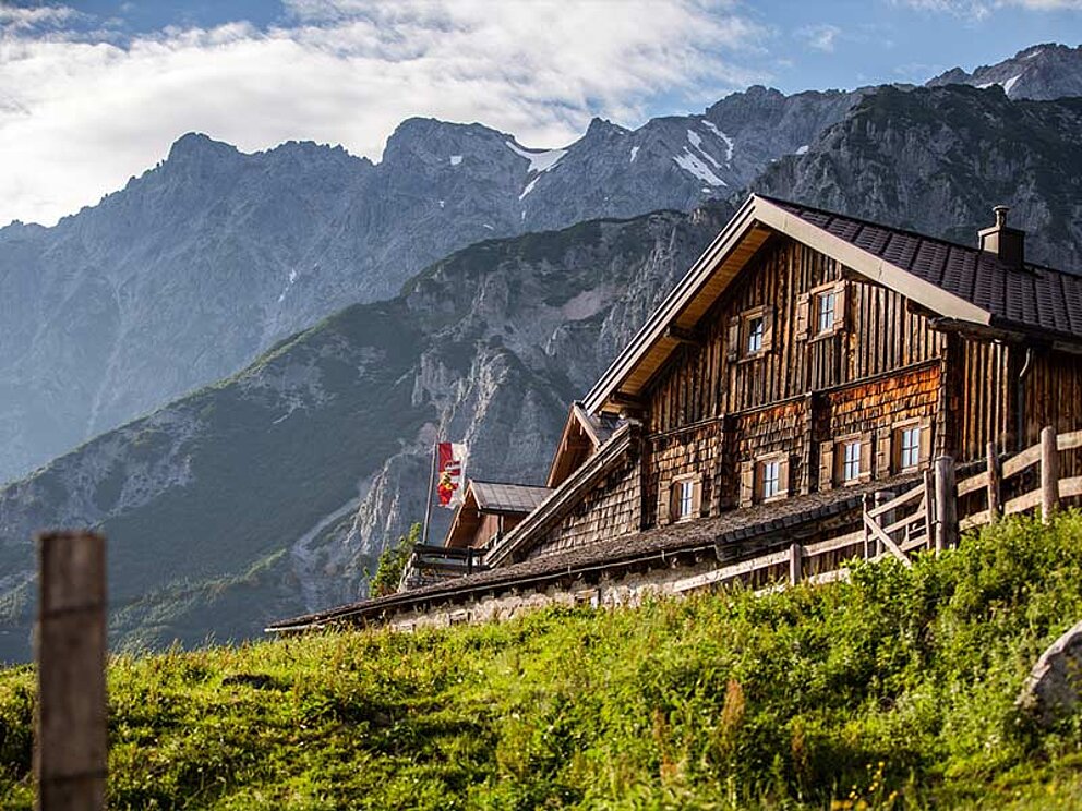 eine Almhütte, im Hintergrund Bergpanorama