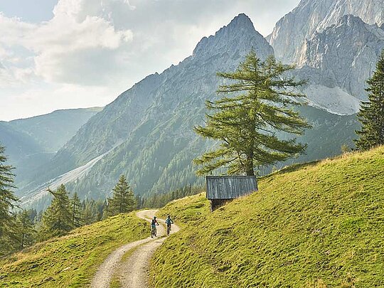 2 Biker am Schotterweg, im Hintergrund der Dachstein