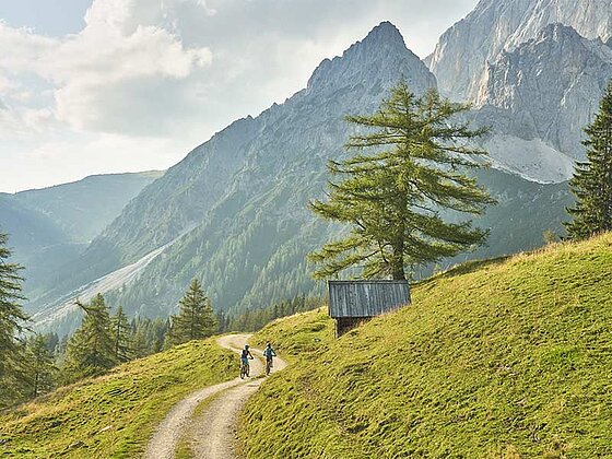 2 Biker am Schotterweg, im Hintergrund der Dachstein