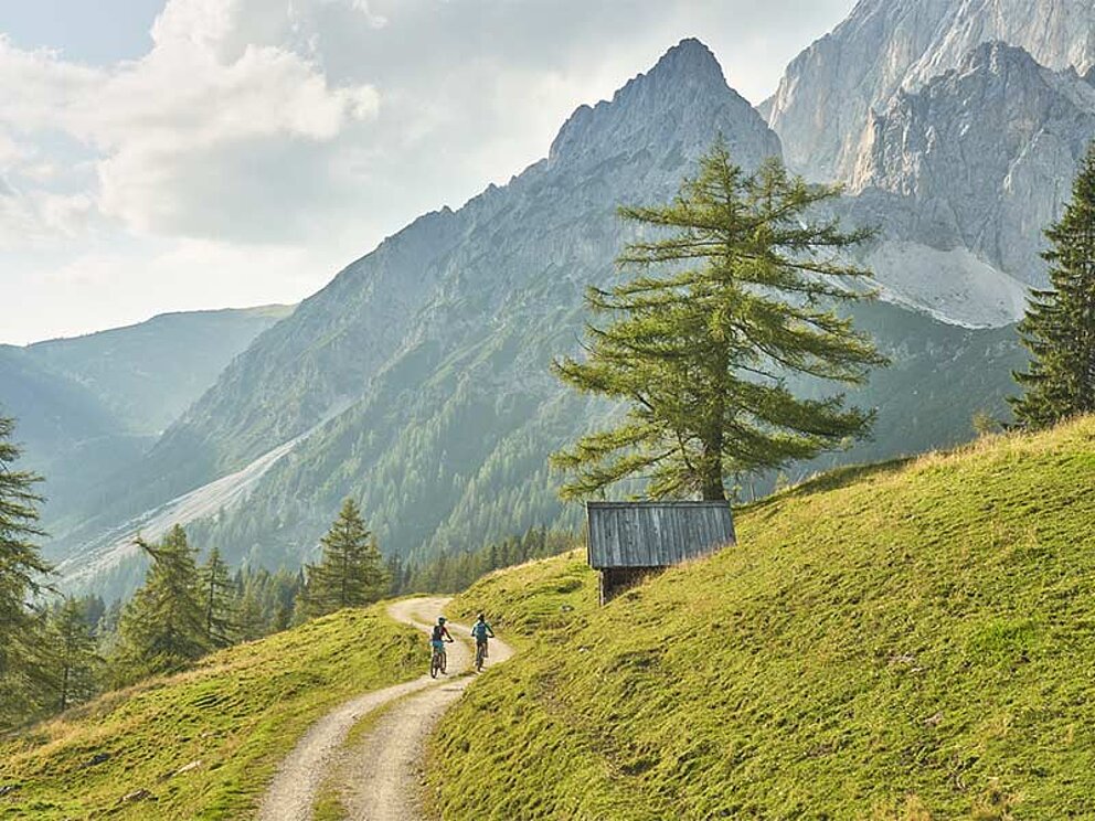 2 Biker am Schotterweg, im Hintergrund der Dachstein