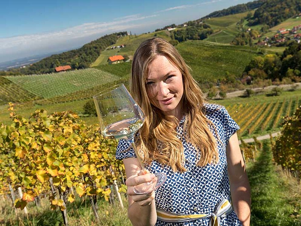 Tamara Kögl präsentiert dem Fotografen ein Glas des selbstgemachten Weißweins.