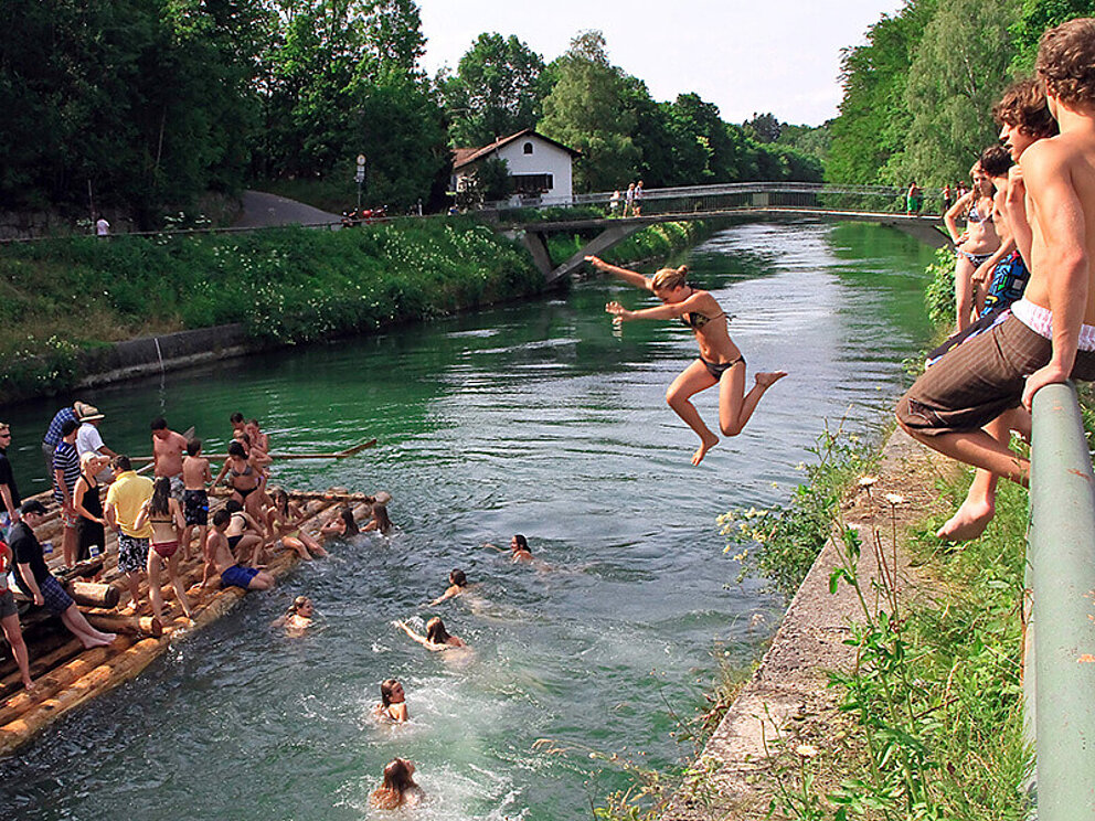 Badegäste springen von Grosshesseloher Brücke in Isar in München