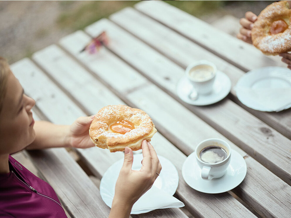 2 Damen im Radeloutfit genießen ihre frischen Bauernkrapfen zum Kaffee.