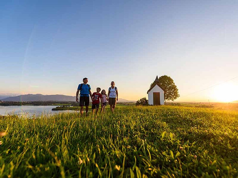 Familie beim Spaziergang im Sonnenuntergang bei der Mesmerkapelle bei Murnau