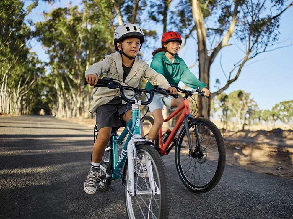 2 Kinder auf woom bikes am asphaltierten Radweg