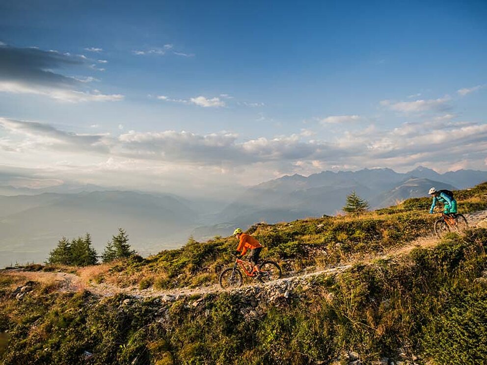 2 Biker beim Downhill auf einem Schotterweg