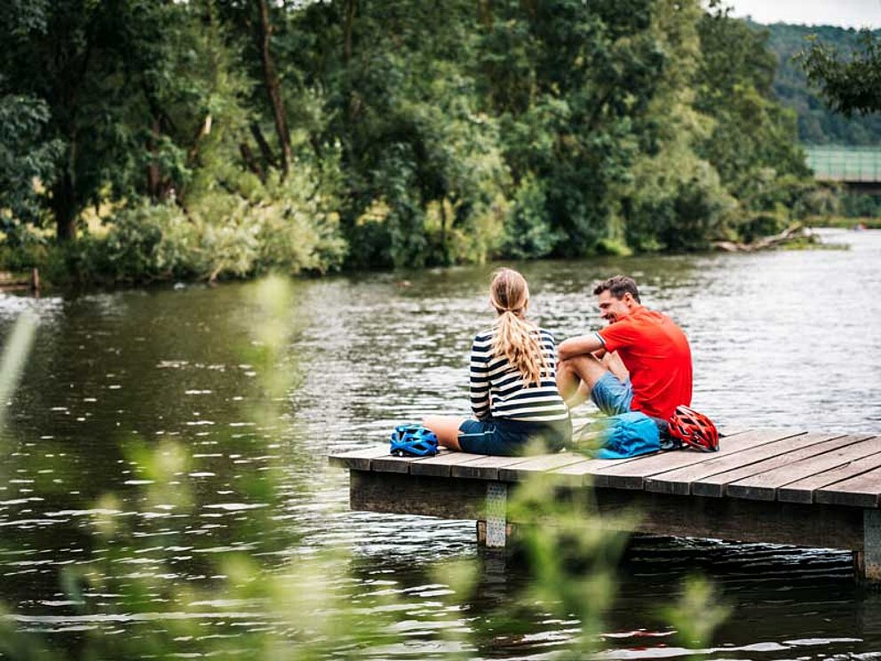 cyclists sit on a landing stage at River Altmühl in Bavaria