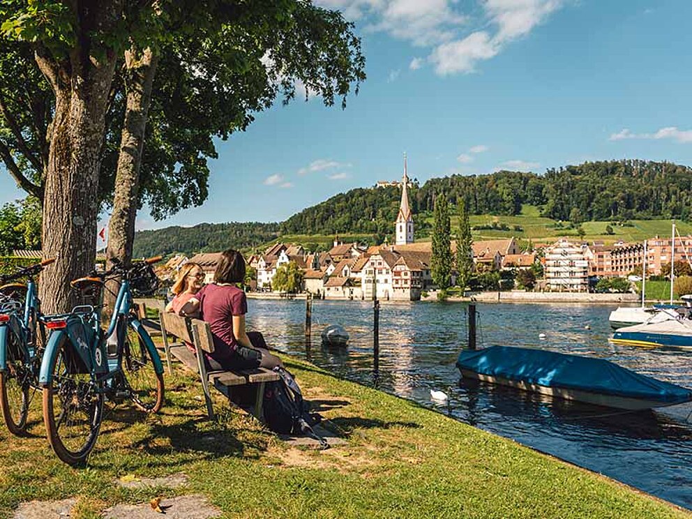 2 Radfahrer auf einer Parkbank am Rhein-Ufer