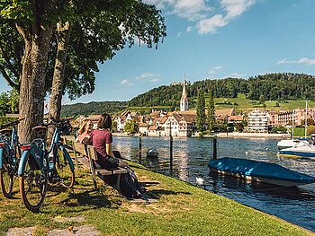 2 Radfahrer auf einer Parkbank am Rhein-Ufer