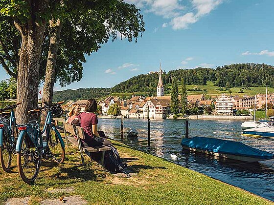 2 Radfahrer auf einer Parkbank am Rhein-Ufer