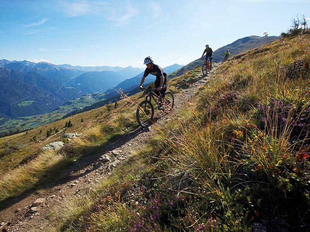 2 Biker auf einem schmalen Trail fahren bergab