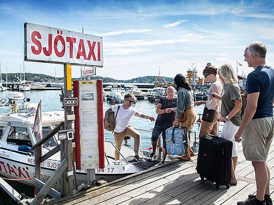 Passagiere mit Koffern gehen an Bord eines Wassertaxis in Stockholm.