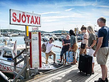 Passagiere mit Koffern gehen an Bord eines Wassertaxis in Stockholm.