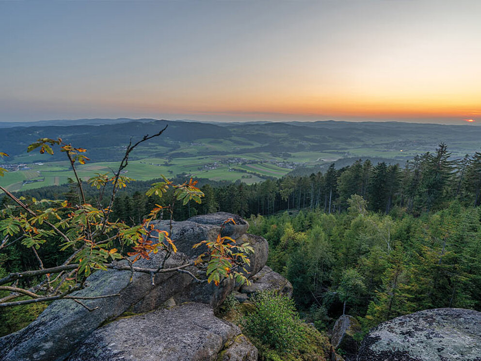 Blick über das Mühlviertel von einem Felsen aus im Sonnenuntergang.