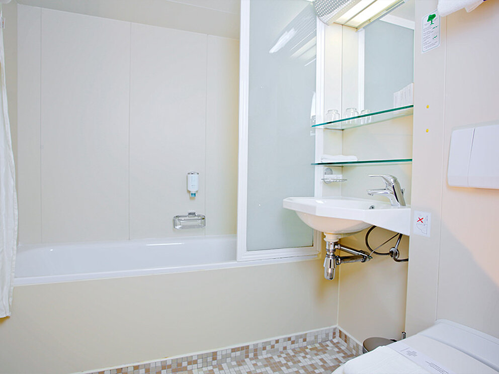 Badezimmer mit Badewanne, Duschwand, Waschbecken und WC