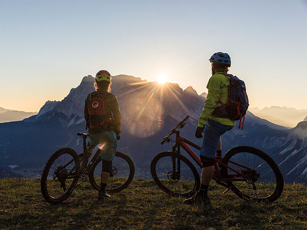 2 Biker im Sonnenuntergang blicken auf den Berg 