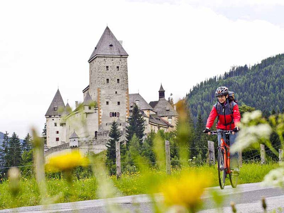 Radfahrer vorbei am Schloss Moosham in der Steiermark am Murradweg
