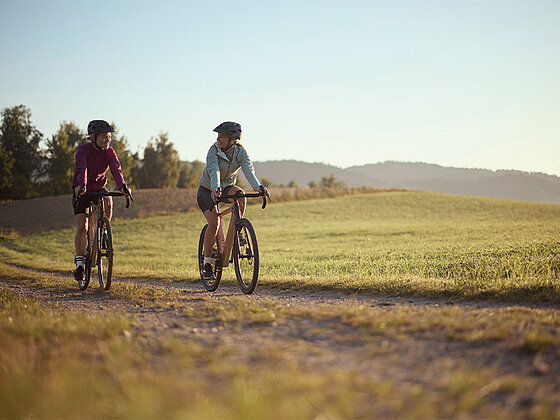 2 Damen auf Gravelbikes am Feldweg.