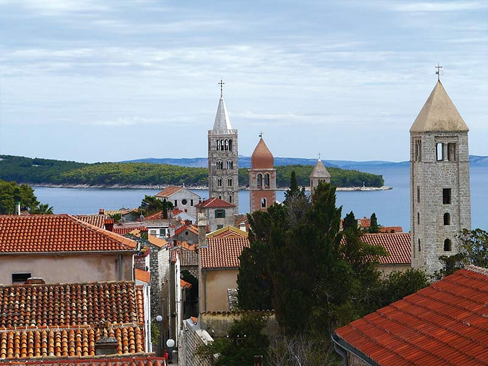 Blick über die Altstadt mit Kirchtürmen, im Hintergrund das Meer