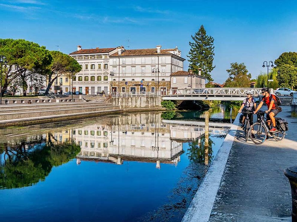 2 Radfahrer am Ufer eines Kanales durch Grado