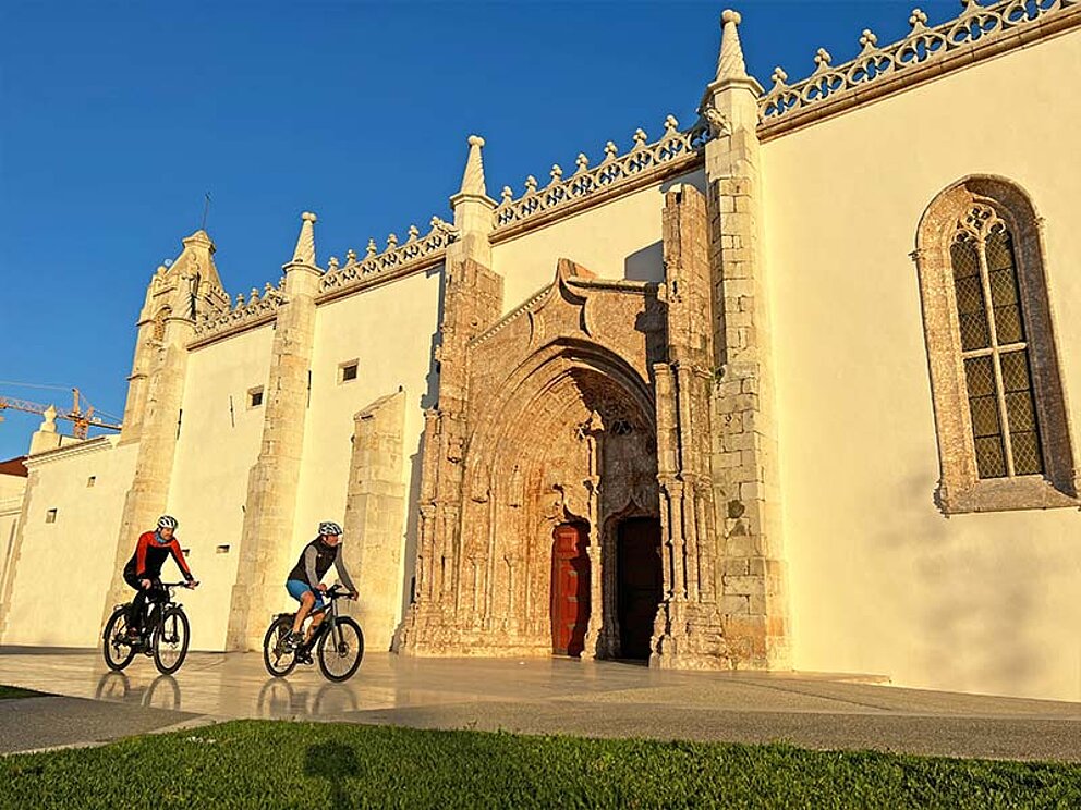 Außenansicht der Kathedrale, davor fahren 2 Radfahrer