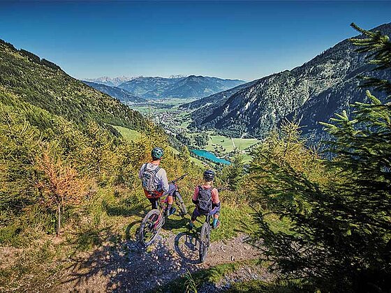 2 Biker auf einer Plattform mit Blick auf den Zeller See und die umliegende Bergwelt
