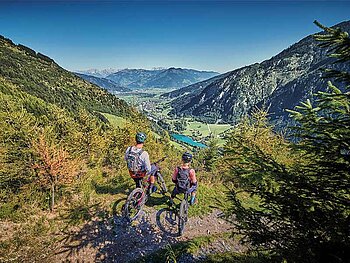 2 Biker auf einer Plattform mit Blick auf den Zeller See und die umliegende Bergwelt