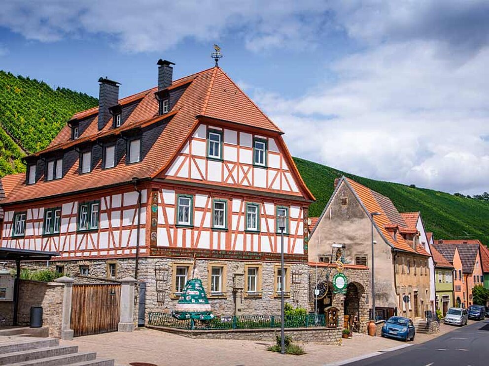 Fachwerkhaus von außen, im Hintergrund Weinberge