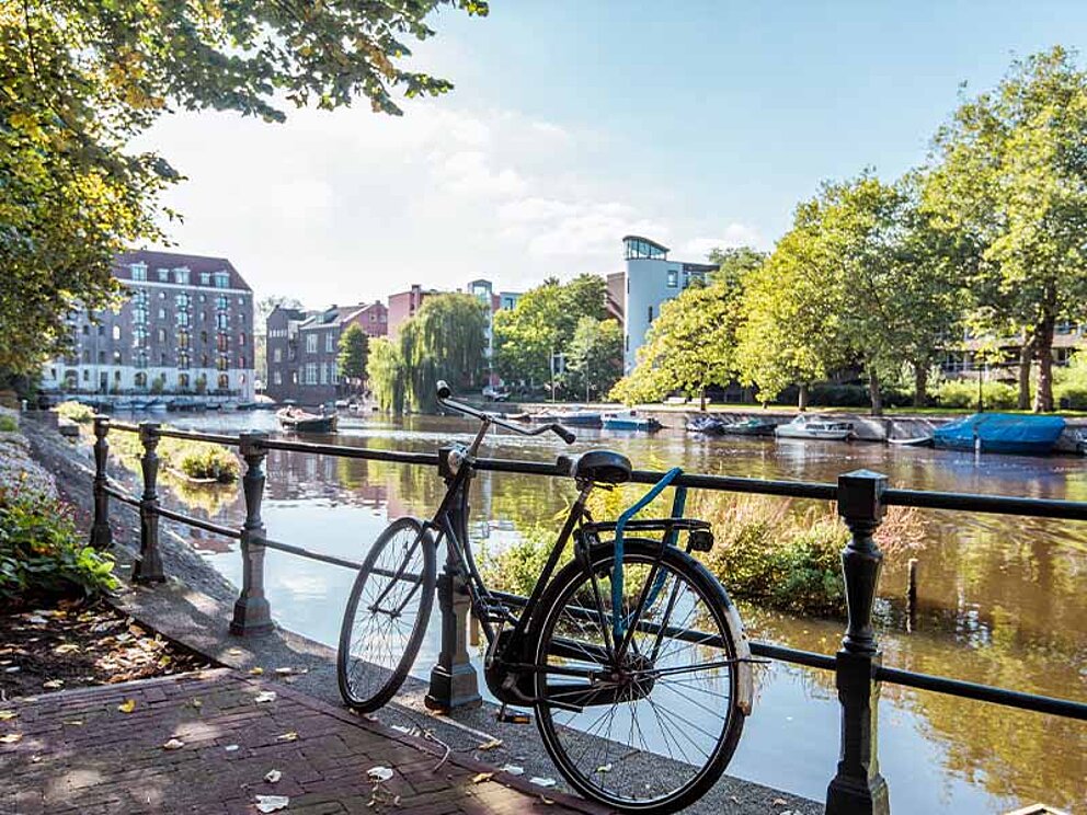 ein Fahrrad ist ans Geländer einer Grachte gelehnt.