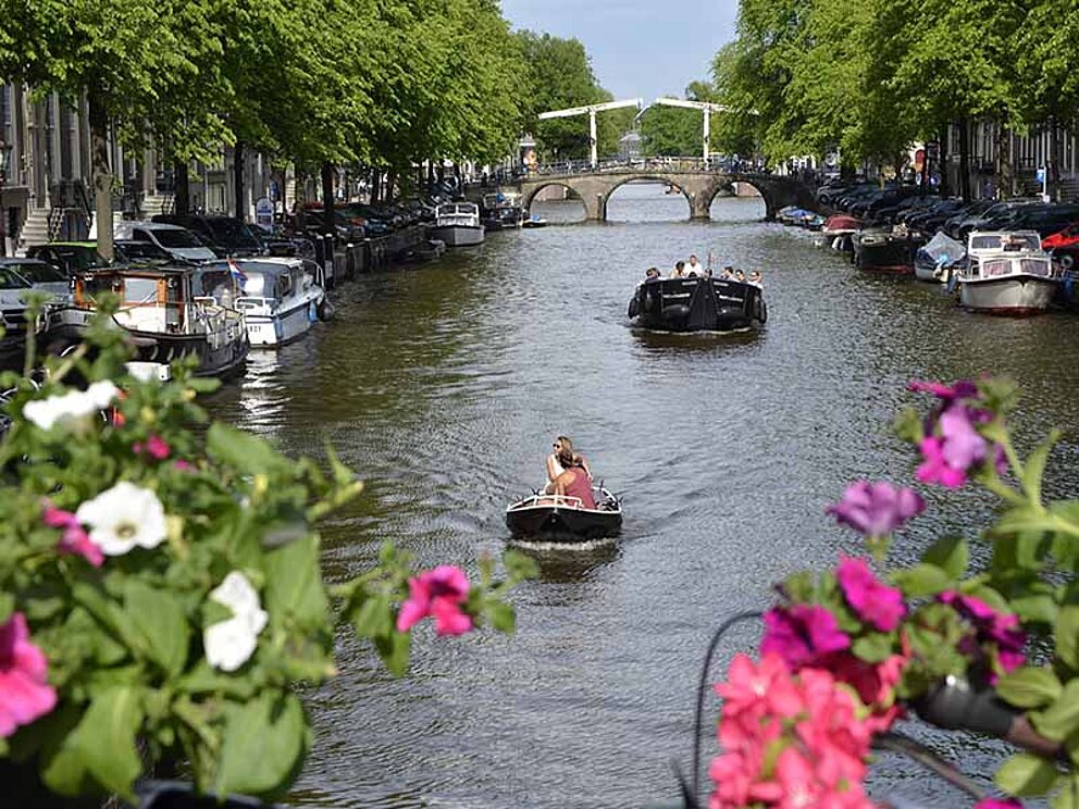 Blick von Brücke auf Kanal mit Booten in Amsterdam