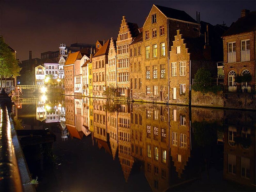 Beleuchtete Häuser unter dunklem Nachthimmel, im Vordergrund die Genter Gracht