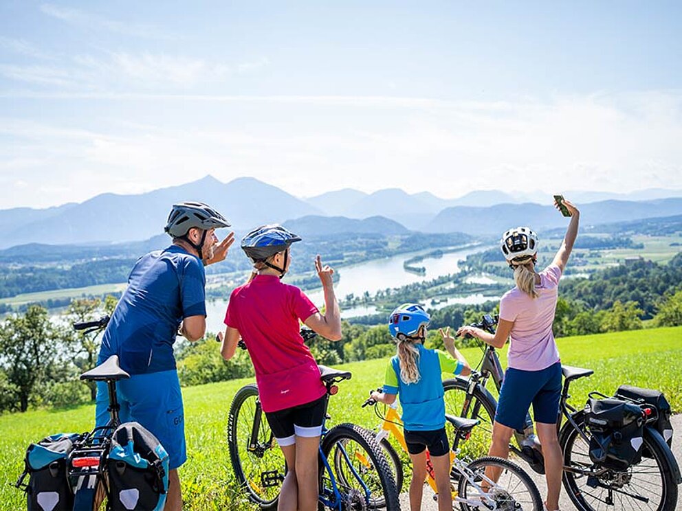 eine Familie macht ein Selfie, im Hintergrund der See und Bergpanorama