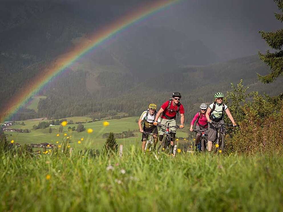 Mountainbike-Gruppe unterwegs nach Gewitter unter Regenbogen