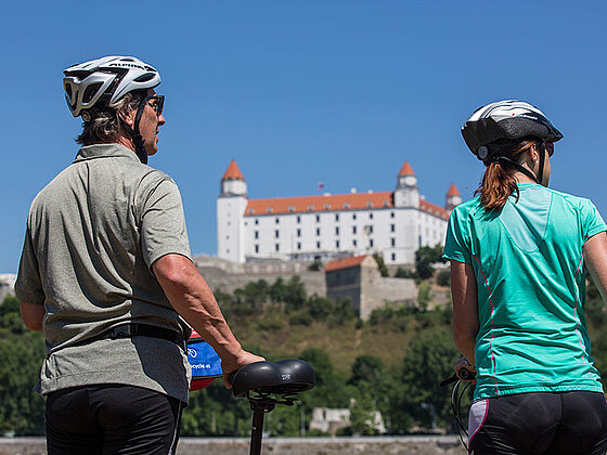 2 Radfahrer von hinten, im Hintergrun das Schloss