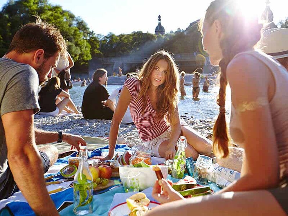 Picknick mit Freunden am Ufer der Isar in München bei Sonnenuntergang