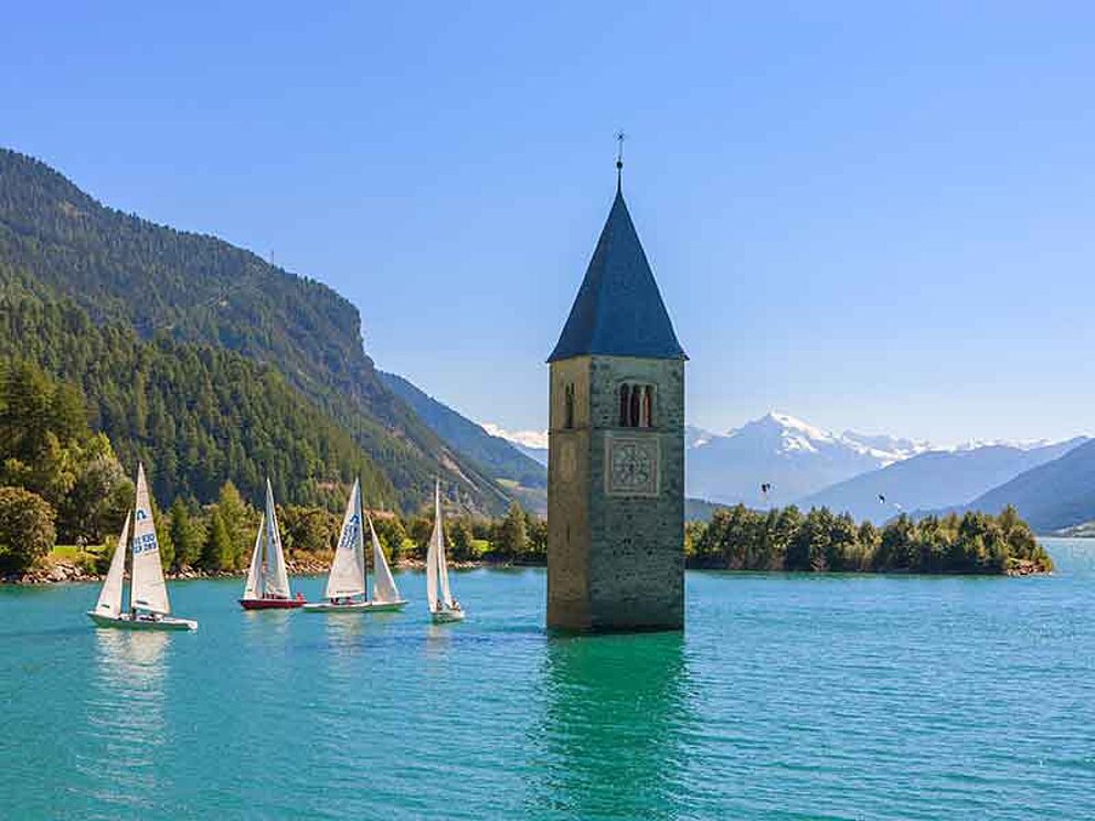 Blick auf den blitzblauen Reschensee in Italien