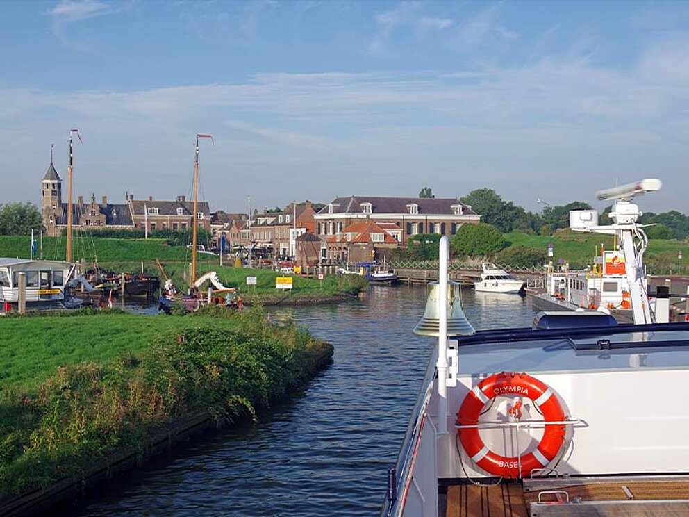 Ein Schiff fährt auf einem Fluss, im Hintergrund die Stadt Willemstad