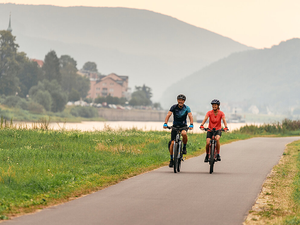 Am flachen Elberadweg radeln ein Mann und eine Frau