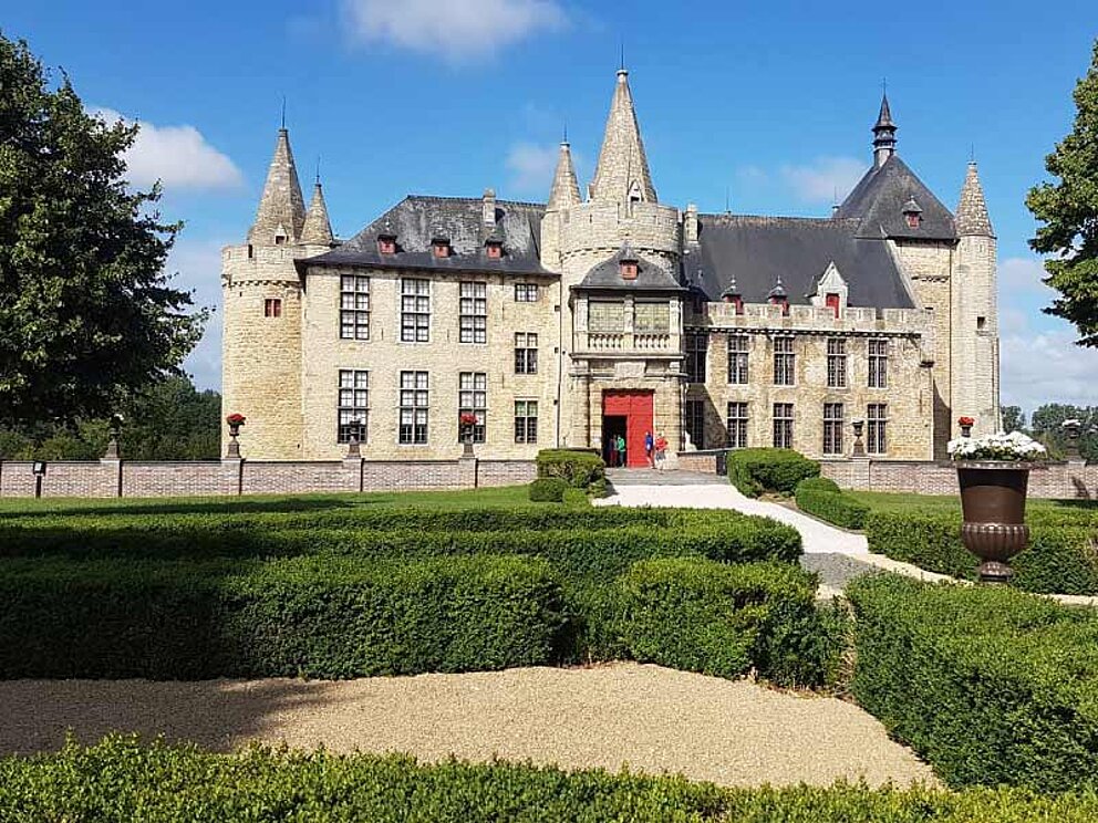 Schloss Larne mit roter Eingangstür, im Vordergrund in Form geschnittene Hecken